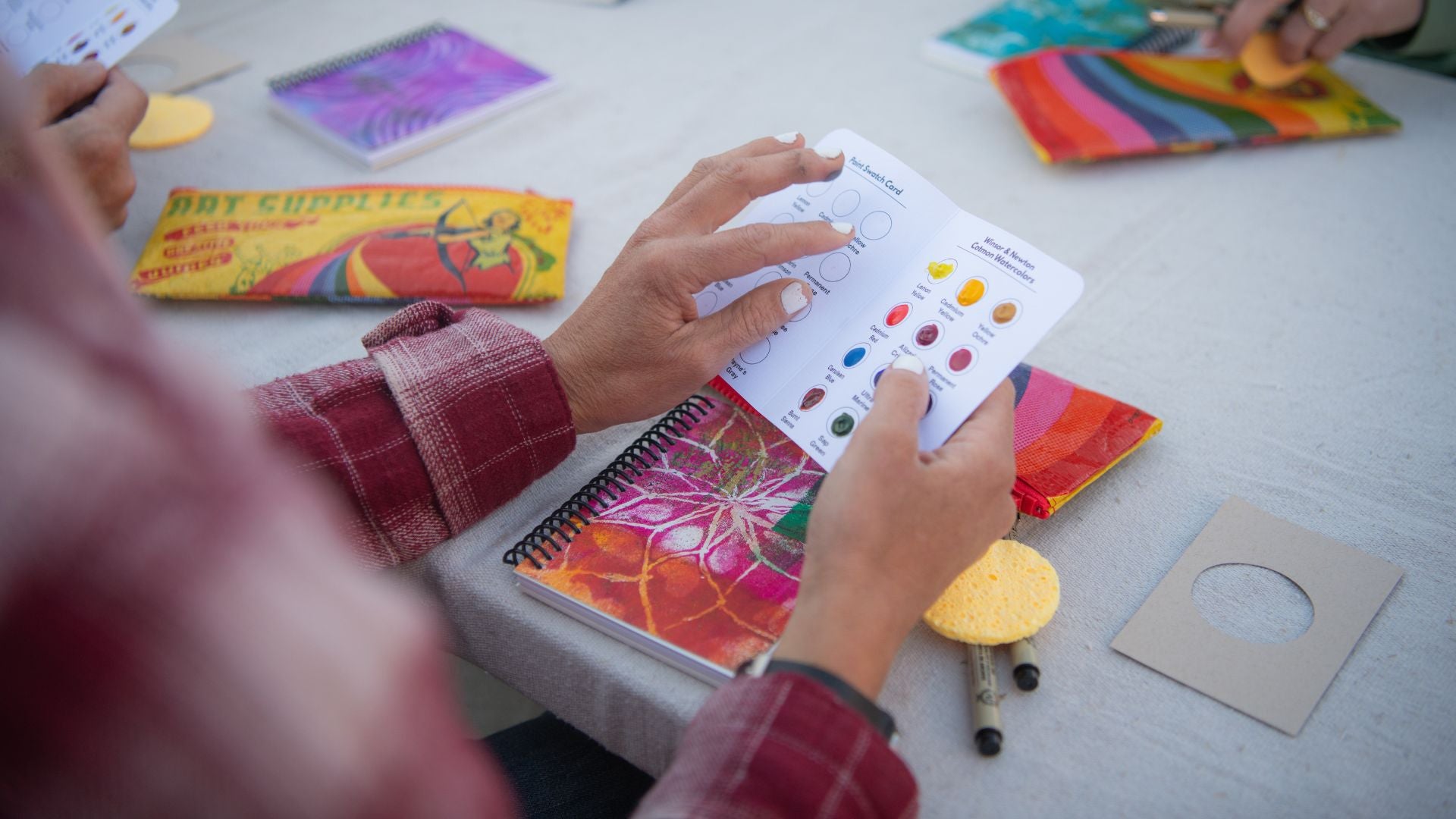 two hands holding a watercolor paint sample card during a watercolor workshop in Zion National Park